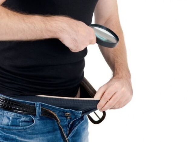 egy férfi lenéz a nadrágjára, és meg akarja növelni a péniszét